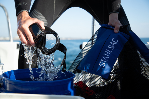 Diver cleaning mask in bucket of fresh water
