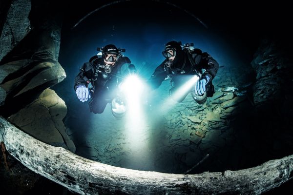 Two divers diving at night with light generated by powerful torches