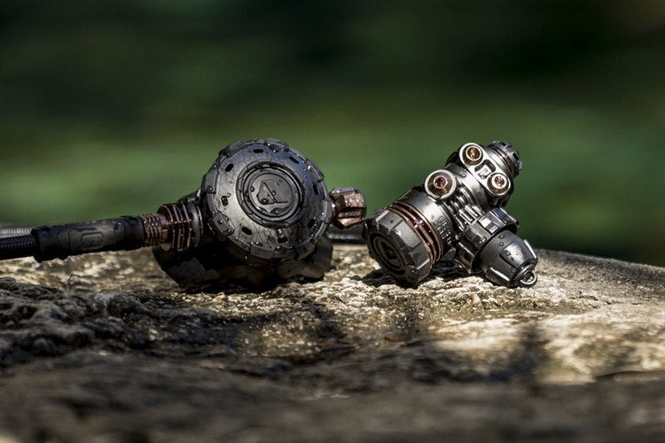 Apeks regulator first stage and second stage resting on a rock at the water's edge