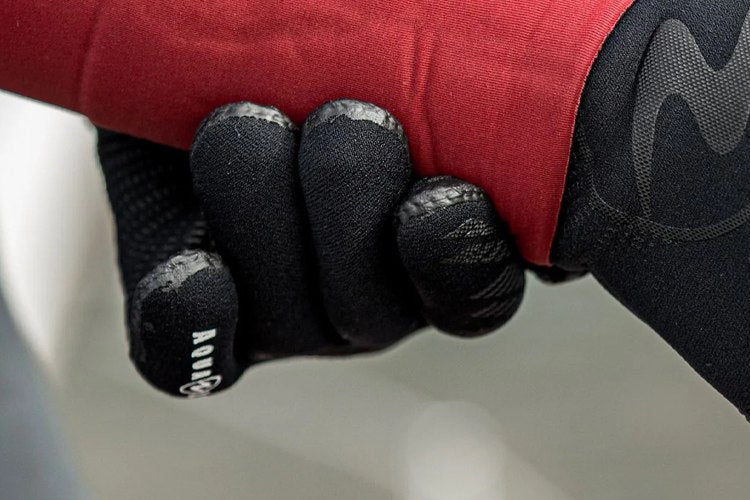Close-up of a diver's neoprene-gloved hand, showing the textured grip pads across the fingers