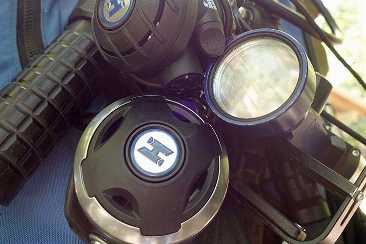 Halcyon second stage regulators and a handheld dive light clipped to a backplate and wing